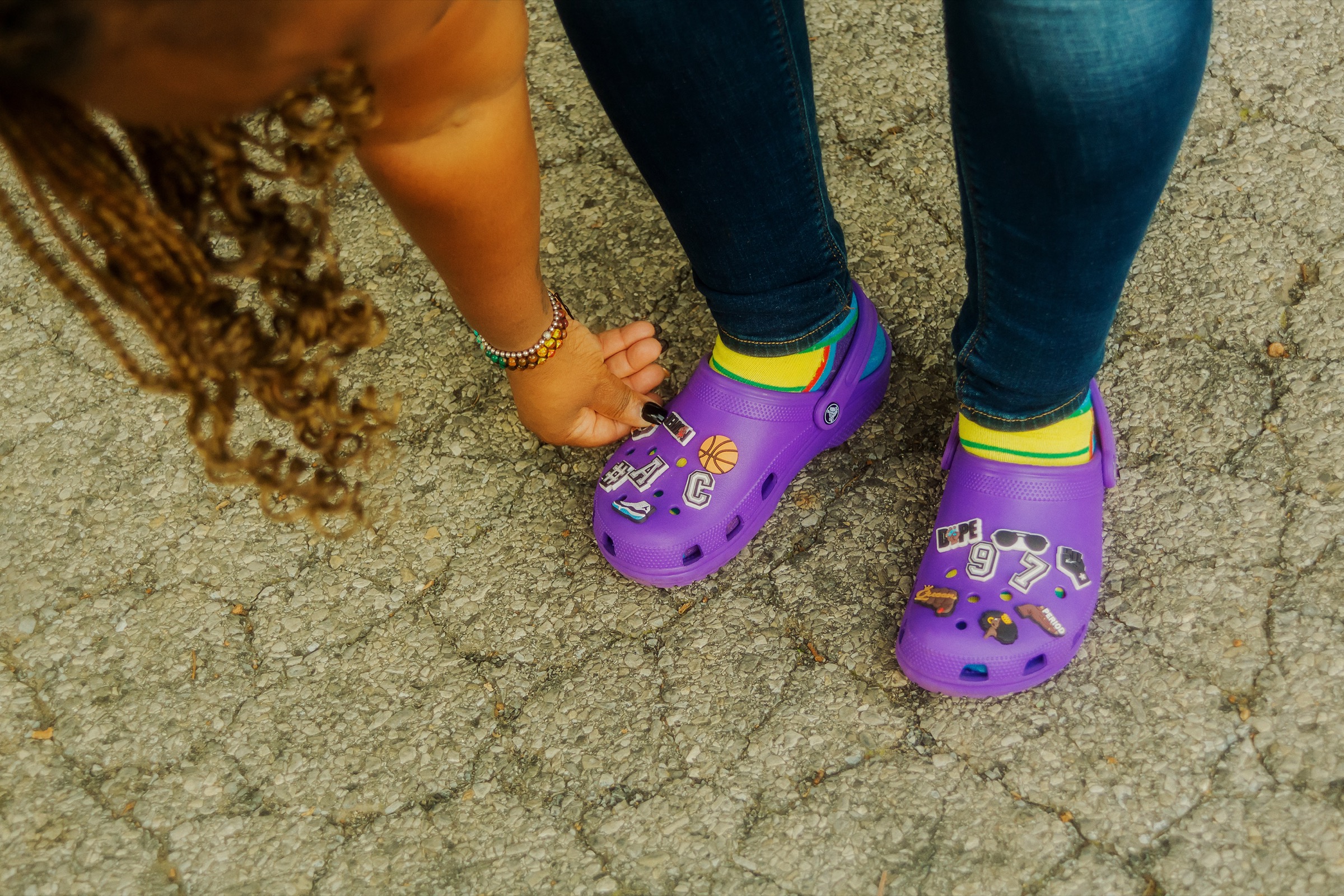 A woman wears a pair of purple shoes decorated with symbols of her son.