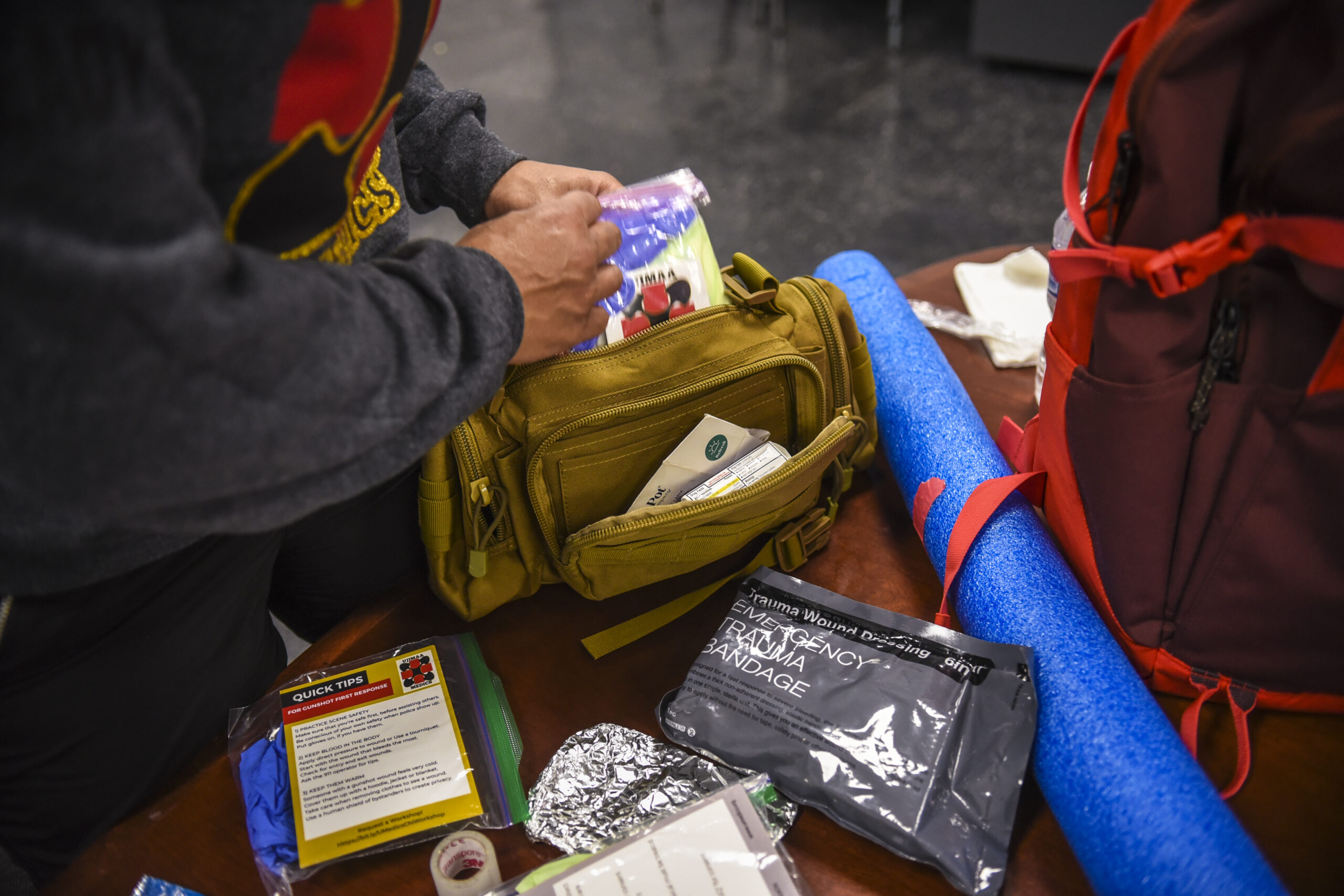 A person unpacks supplies from a medical kit, including an emergency trauma bandage.
